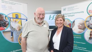 A man and a woman standing in front of pull up banners that read "Dublin Southwest Integrated Care Programme for Older Persons"