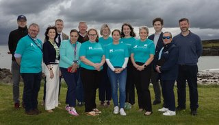 A group of people standing on Clare Island. Some are wearing blue t-shirts that read Mayo IGPOP.