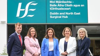 Four women and a man standing in front of a building sign that reads 'HSE Dublin and North East Surgical Hub'.