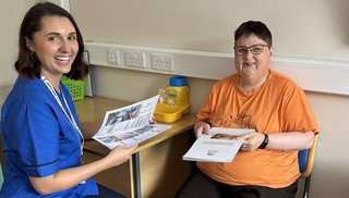 A healthcare worker and patient sitting at a table holding information leaflets.