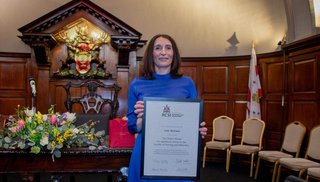A woman holding an award certificate at a conference