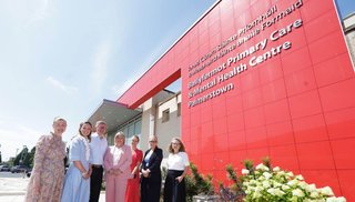 A group of people standing in front of a building. There is a sign that reads 'Ballyfermot Primary Care & Mental Health Centre Palmerstown'.