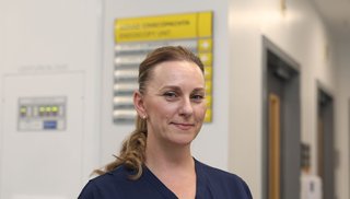 A female healthcare worker in a hospital setting smiling into camera