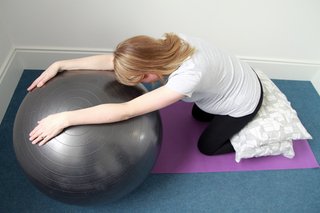 Demonstration of child's pose with a gym ball.