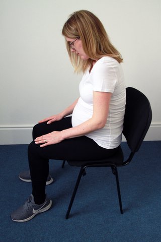 Image of woman on a chair, slouching forward as her back curves