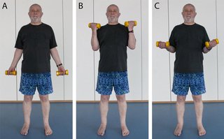 man standing and gently lifting light weights to the shoulder
