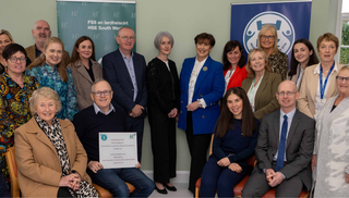 18 people in front of pull up banners looking towards the camera and smiling