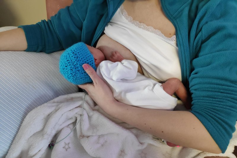 A woman breastfeeding a premature baby on her left arm