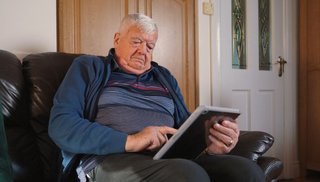 A man holding an iPad sitting on a couch