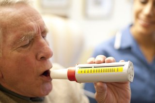 Person blowing into a peak flow meter.