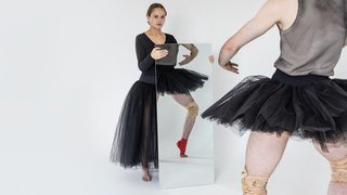 A woman holding a mirror to show an image of a ballerina