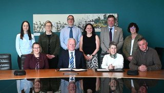 A group of people sitting and standing at a boardroom table