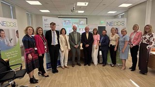 Twelve people standing in an indoor setting and smiling for the photo