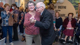 Two people waltzing and smiling while other people look at them