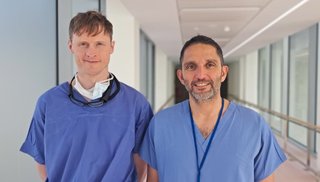 Two men standing side by side and smiling at the camera