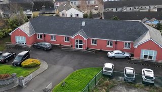 Large detached bungalow style red building with cars parked in front of it
