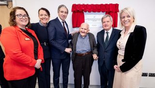 6 people smiling at the camera, standing in front of a red curtain