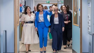Group of people walking through a hospital corridor with three women in the front