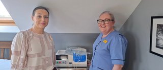 Two women standing beside a medical device and smiling at the camera.