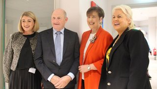 Three women and one man standing looking into a camera smiling