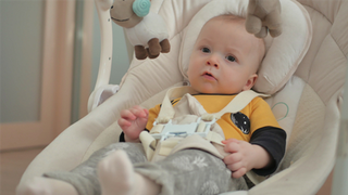 A baby lying in a baby bouncer