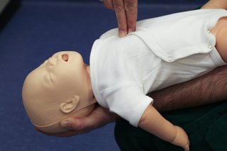 First aider demonstrating chest thrust with an infant CPR dummy