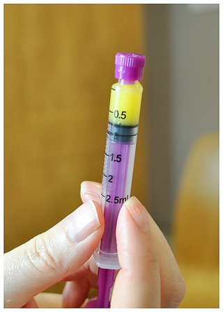 A feeding syringe partly filled with yellow colostrum