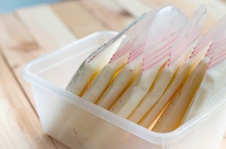 Single-use storage bags containing frozen breast milk stacked in a container