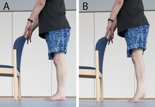 man holding back of chair and lifting heels off the ground