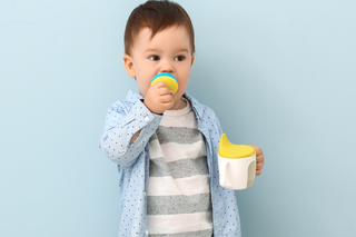 Child using a feeder cup to drink expressed milk