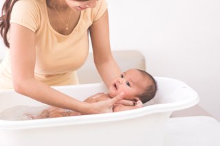 A mother holding a baby in a baby bath