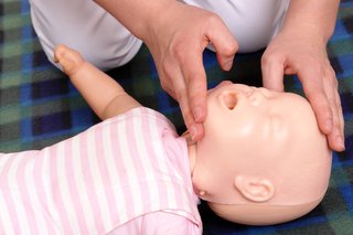 Image shows person opening a baby's airway with one hand on their forehead and the other hand tilting their head back