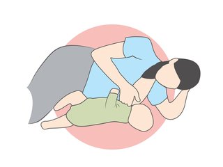 mother lying on her side on a bed with baby lying in front while breastfeeding