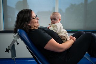 A woman propped up against an adjustable bed with a baby on her chest