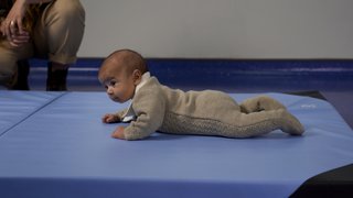 A baby lying on a mat with their head looking up.
