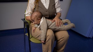 A woman sitting on a chair with a baby on her lap.