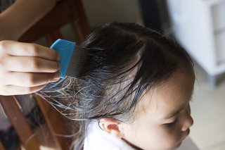 A child with long, wet hair having their hair combed. The comb has long, fine metal teeth