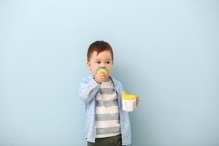 Child using a feeder cup to drink expressed milk
