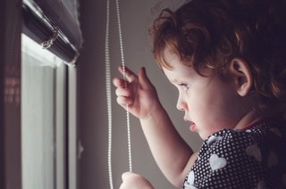 Girl holding pull-cord for blinds - these are a strangulation risk