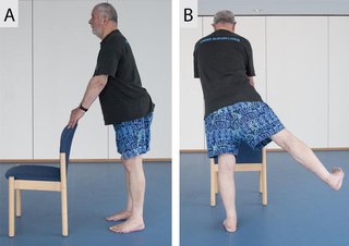 man holding back of chair and lifting one leg to the side