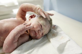 new born baby covered in white greasy substance